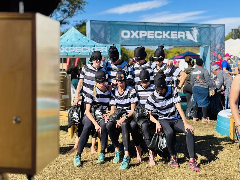 A team in striped shirts and masks posing for the photobooth at the Oxpecker Trail Run