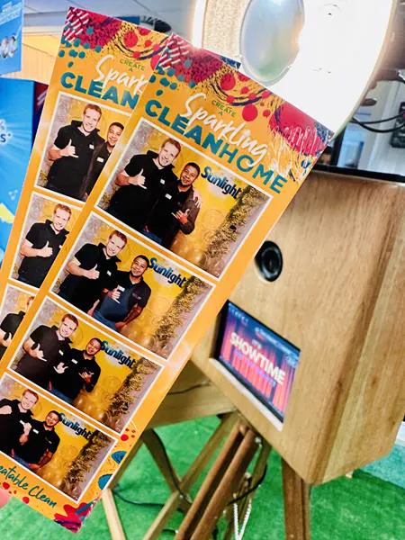 Sunlight Sparkling Clean Home branded photostrips held beside the Retrobooth at a brand activation