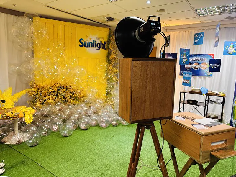 The Retrobooth at the Sunlight brand activation with a yellow backdrop and bubble balloon installation