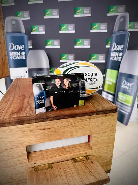 A Dove Men and Care branded print on the printer box beside a Springbok rugby ball at a brand activation