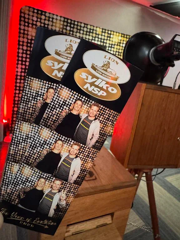 Lion Match Syiko NSP branded photostrip held beside the Retrobooth at a corporate year-end function