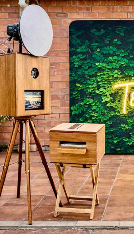 The Retrobooth and printer on a patio beside a green foliage wall and neon sign at a Durban event