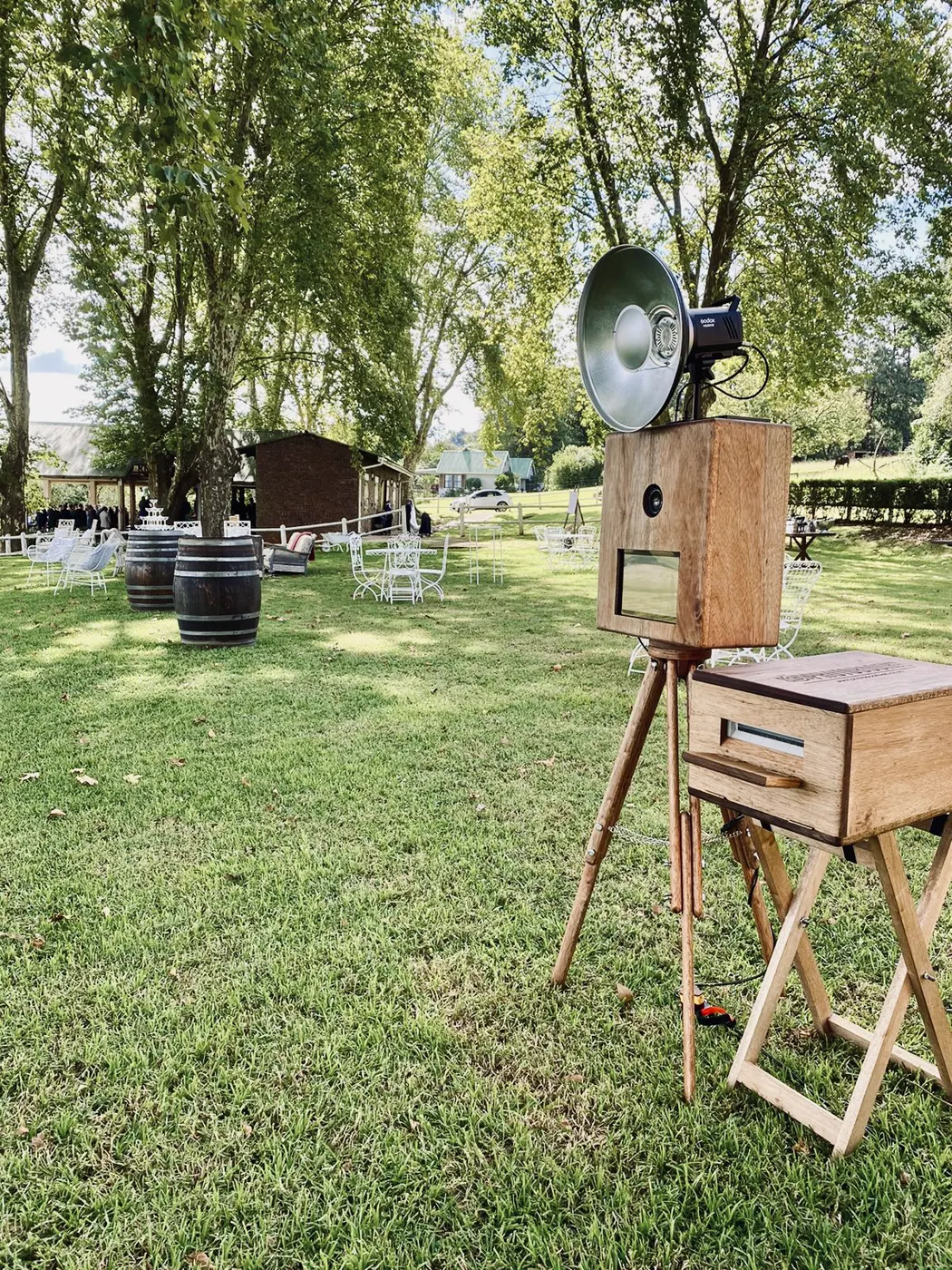 The Retrobooth on the lawn at a garden wedding with wine barrels and white wire furniture
