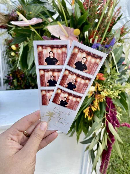 Two Carole and Trent branded photostrips held in front of tropical wedding florals in Durban