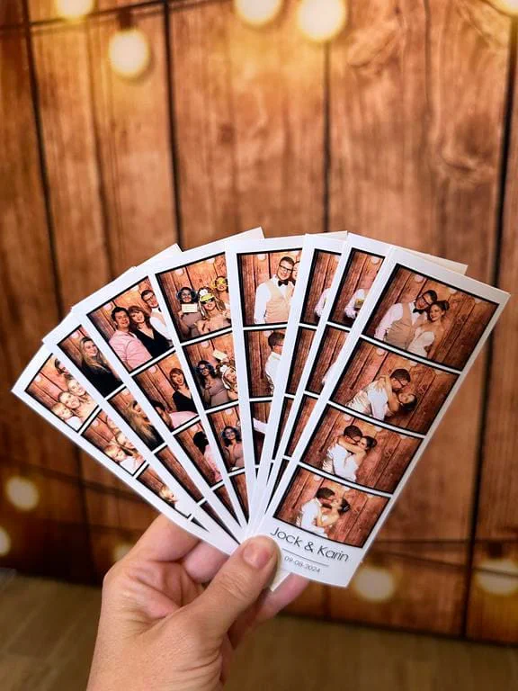 A fan of Jock and Karin wedding photostrips against the wood panel backdrop with festoon lights
