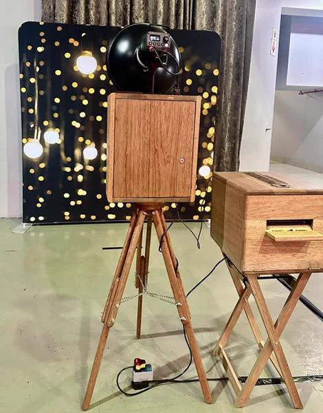 The Retrobooth and printer in front of a black and gold bokeh backdrop at a Durban function