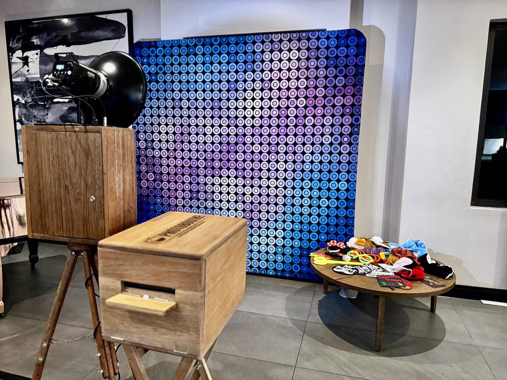 The Retrobooth, printer and props table beside a blue and pink retro dot backdrop at a corporate event