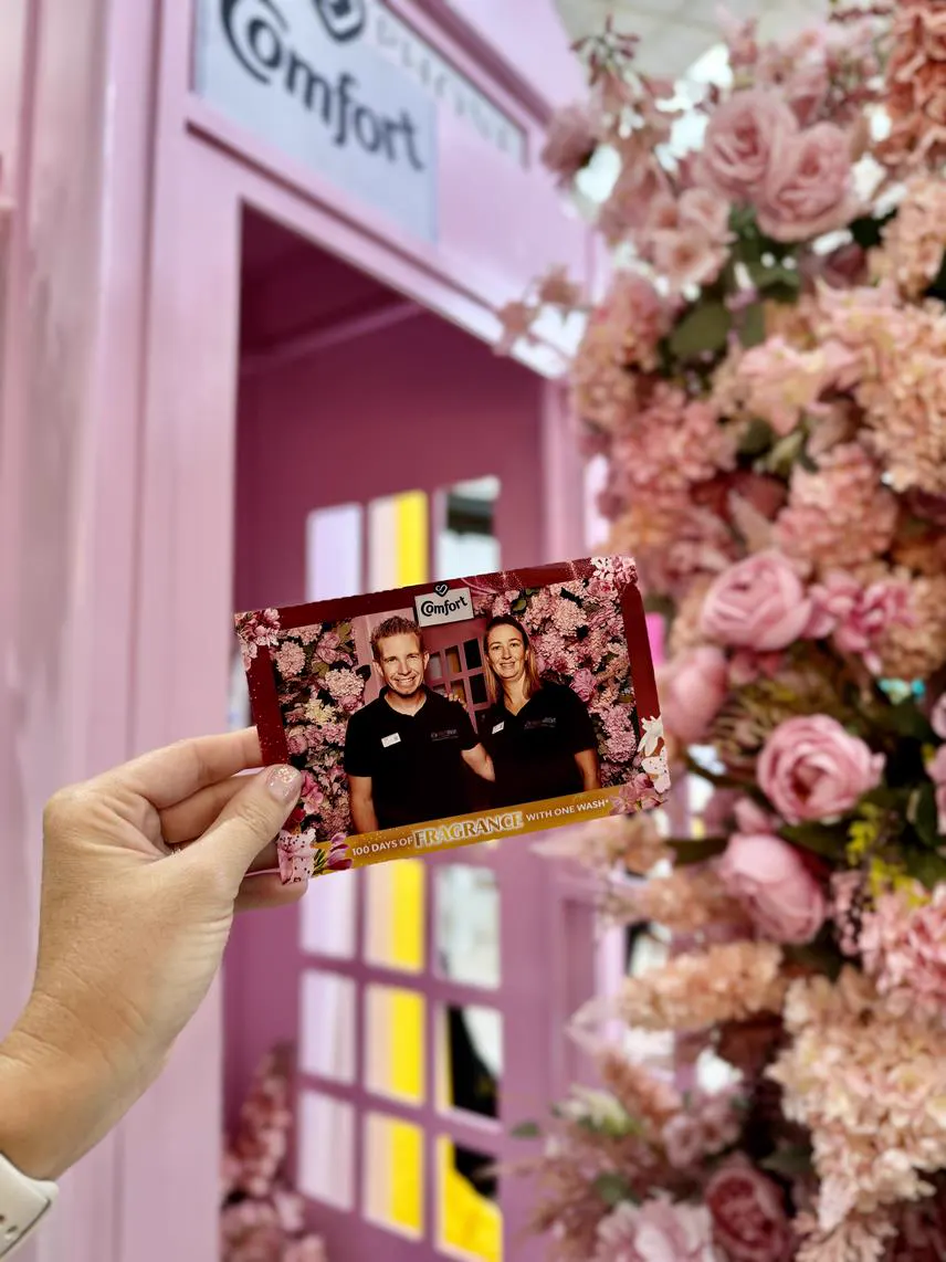 A Comfort branded print held in front of the pink floral set at a Durban brand activation