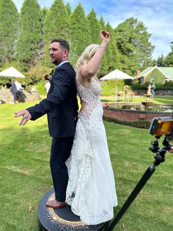 A bride and groom standing on the SPIN360 platform on the lawn at a Durban wedding venue