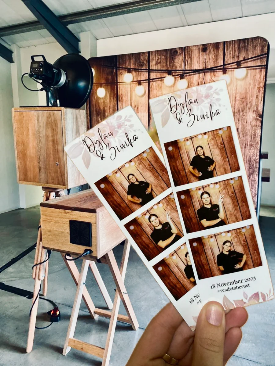 Two instantly printed photostrips from the Retrobooth held up at a wedding